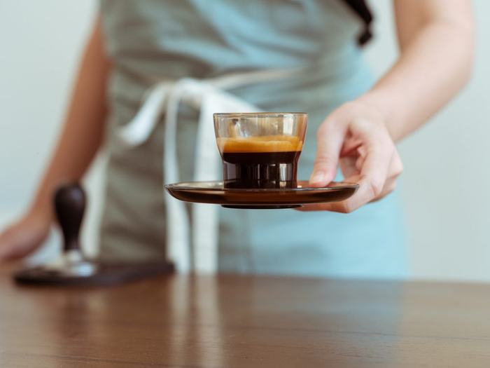 Barista serving an espresso across a wooden café counter