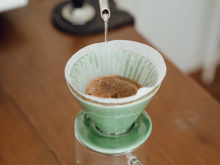 Pour-over coffee brewing in a green ceramic dripper