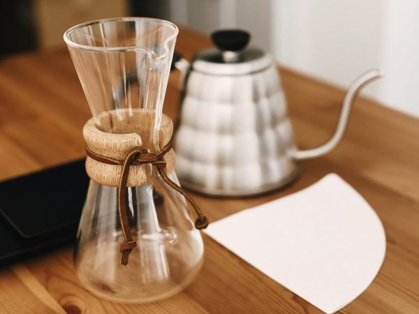 Glass pour-over brewer and gooseneck kettle on a wooden counter